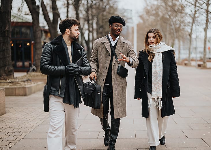 A group of stylish young entrepreneurs walking together outdoors engaged in a conversation.