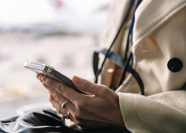 A person checking flight details from her smartphone in the airport.