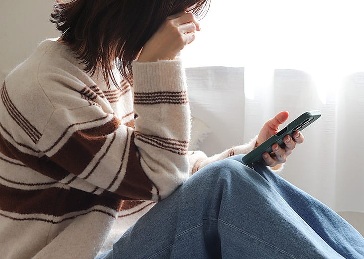 A person putting her head down while checking her smartphone.