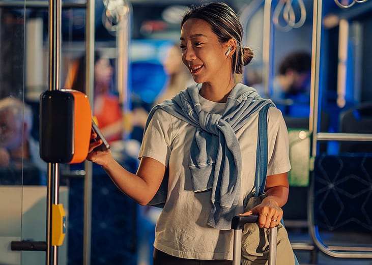 A female tourist paying for bus fare using smartphone NFC technology