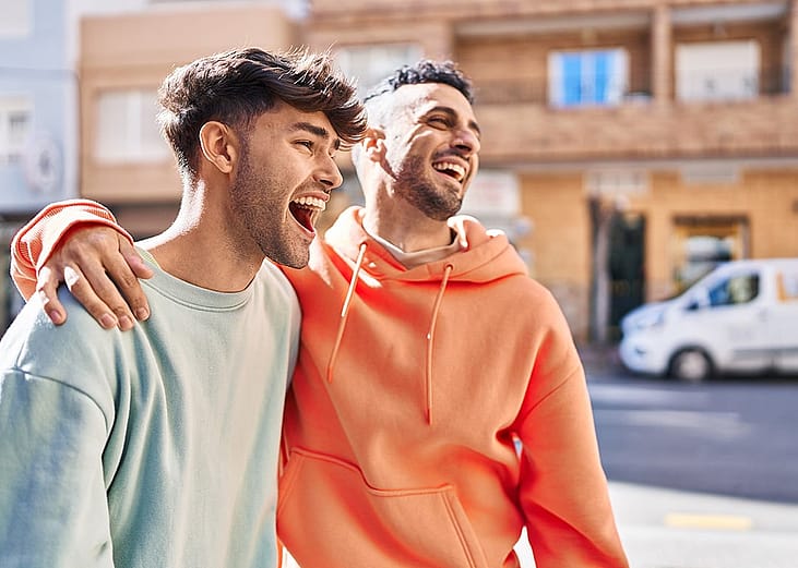 Friends enjoying a good time while side hugging each other outdoors.