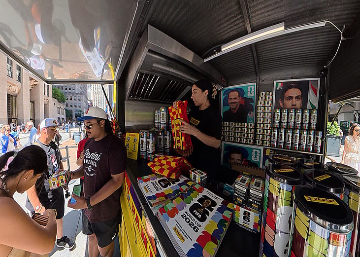 Sports fans buying World Cup stickers at a vending cart in New York City, USA.