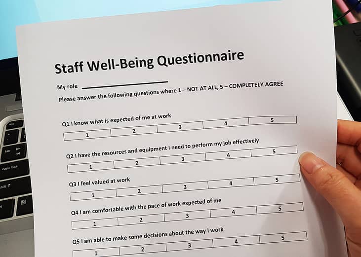 A staff well-being questionnaire held by a person's hand. 