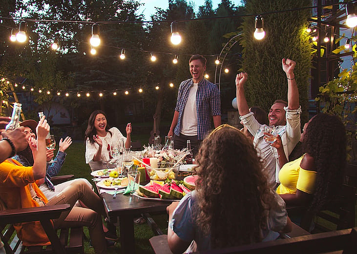 A diverse group of friends having a party at a backyard at night.