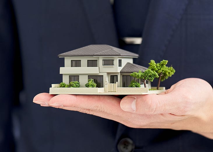 A businessman holding a small-scale figure of a house.