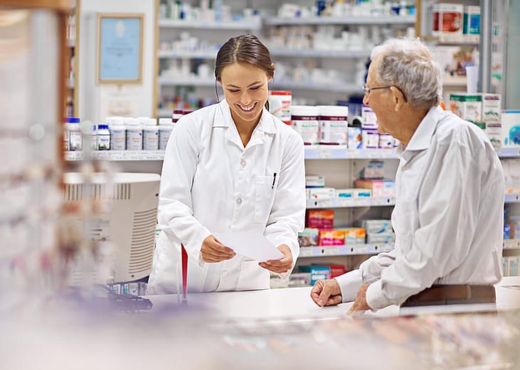 A pharmacist helping an elderly customer for prescription medicines at the counter.