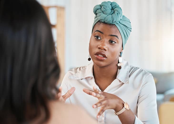 A young black female entrepreneur in discussion with a colleague.