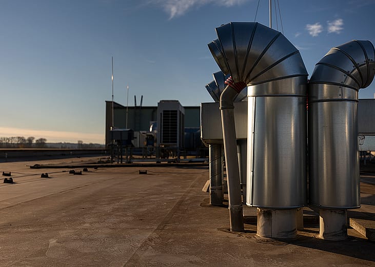 External air conditioning units and ventilation system installed on an industrial building's roof.