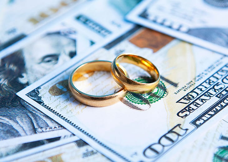 A pair of wedding rings on top of US banknotes.