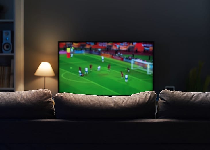 A football match displayed from a smart TV at a home's living room.