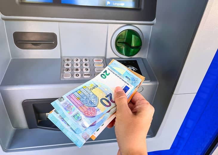 Person withdrawing Euros from an ATM.