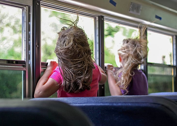 Children looking through the bus windows during a trip.