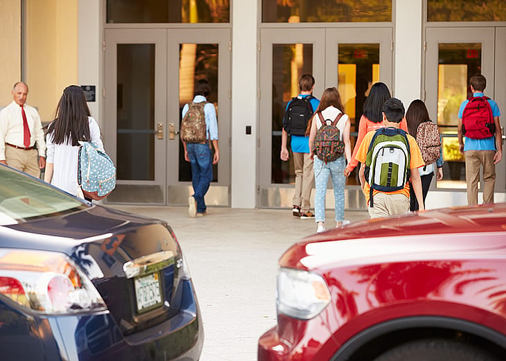 High school students being dropped off by their parents at their campus' entrance.