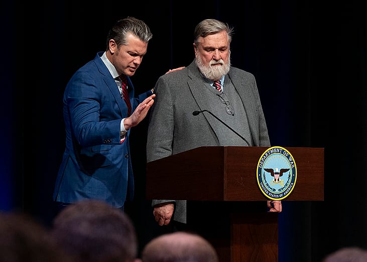 Pete Hegseth and Douglas Wilson stand at a podium during a Pentagon prayer service in February 2026.