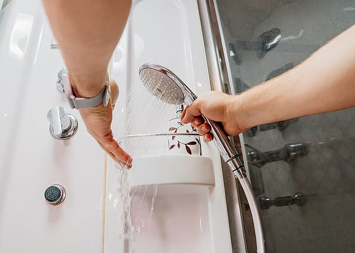 Person testing the water temperature on a shower hose.