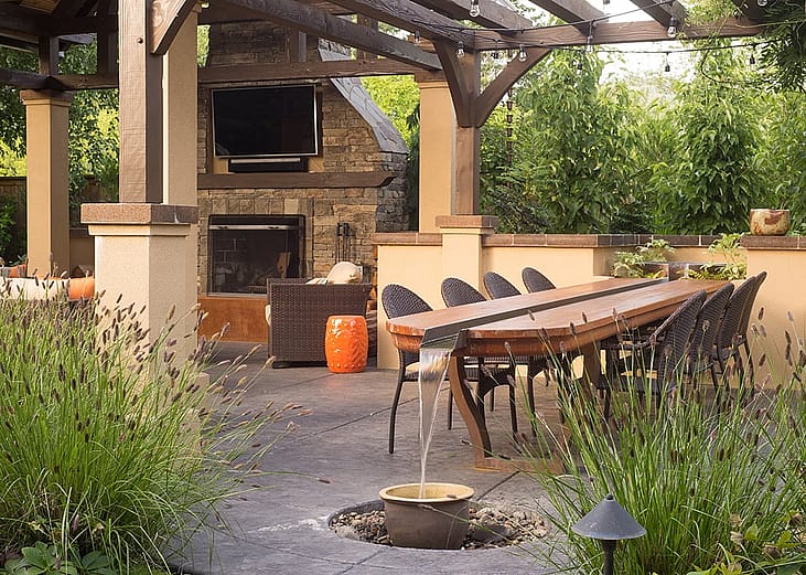 An upscale backyard terrace featuring perennials and with a custom designed shelter and fireplace.