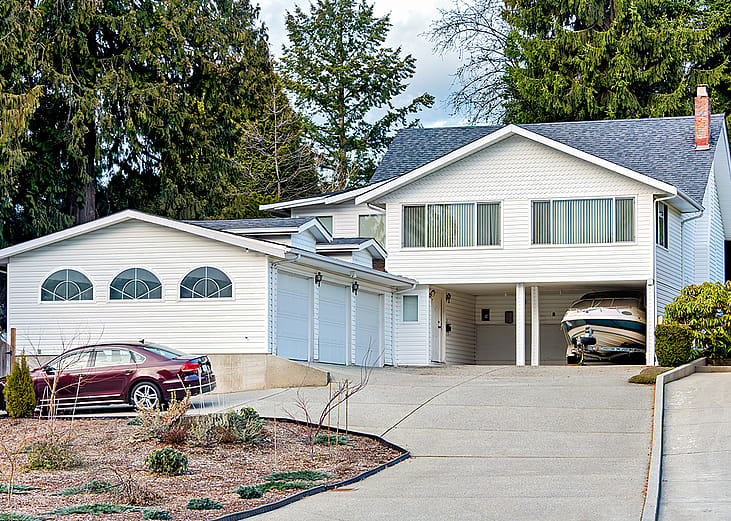 A family house with a private car and a small boat on trailer parked under the carport.