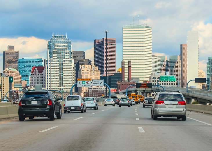 Cars driving to downtown area with the Boston skyline in the background.