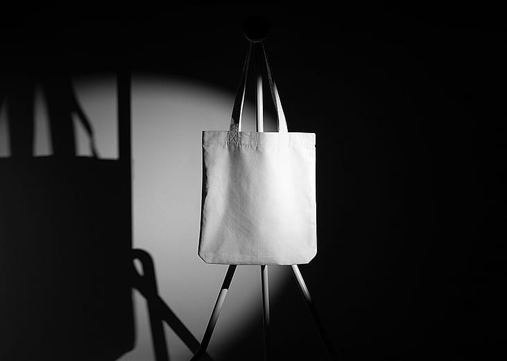 A mockup template of a tote bag on a metal hanger taken in a photo studio.