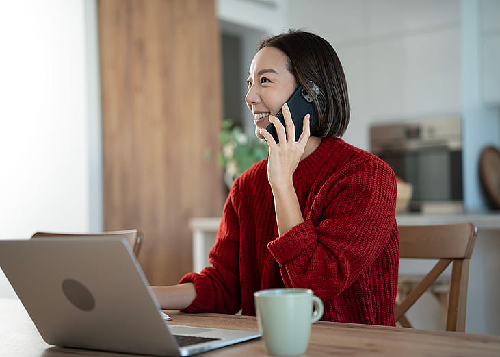 A young businesswoman on the phone while working from home.