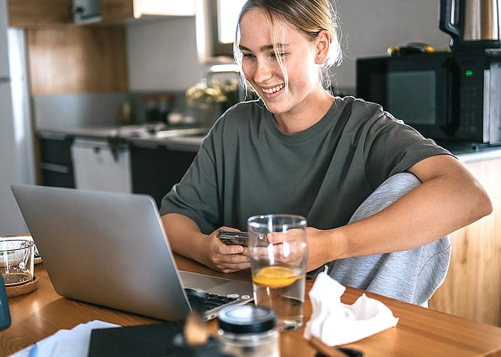 A young adult working remotely at her cozy kitchen at home.