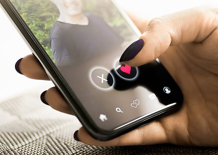 A person checking a profile of another person from a dating application in her smartphone.