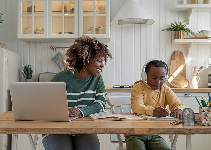 A mother checking his son's progress on a school homework while working at home.