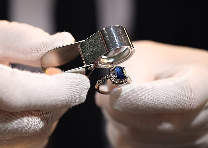 A jewelry appraiser using a loupe to evaluate a bejeweled ring.
