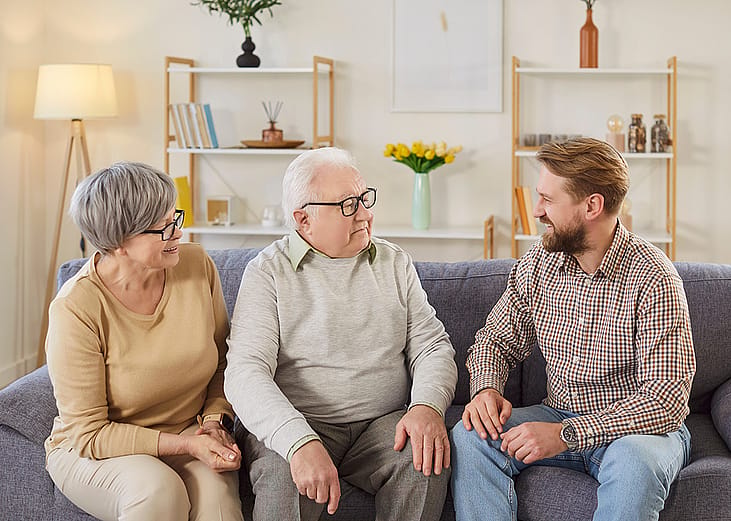 Senior parents and their adult son having a discussion at home.