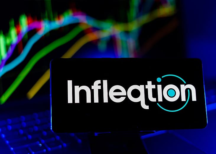 Infleqtion quantum technology corporation logo displayed from a smartphone's screen with a financial stocks chart in the background.