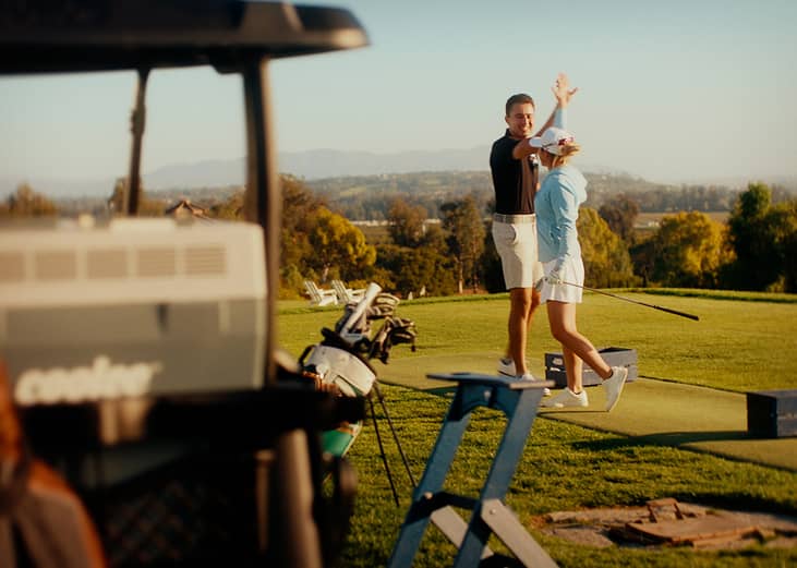 Golf players high five in the air during a game.