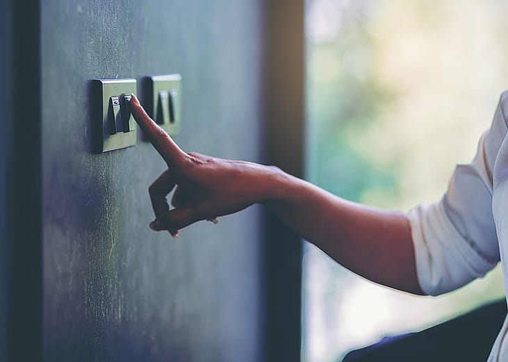 Person turning off a light switch at home.