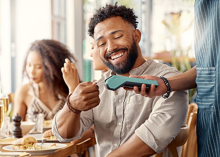 Man happily paying for meal at the restaurant with a credit card.