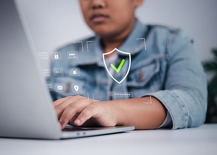 A teenage boy using the internet illustrated with cybersecurity and data privacy graphics.