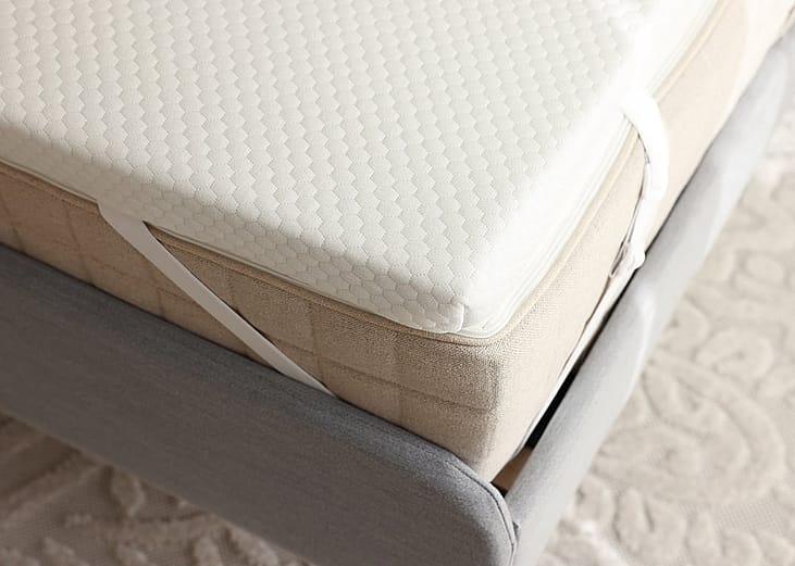 A grey bed with a brand new memory foam mattress.