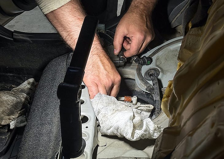 A mechanic checking car fuel pump pressure test during vehicle maintenance diagnostics.