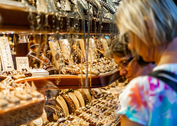 Women looking at various jewelry collections at a store.