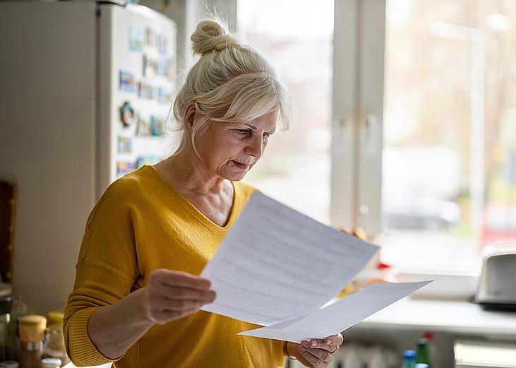 A senior woman reviewing her bill statements.