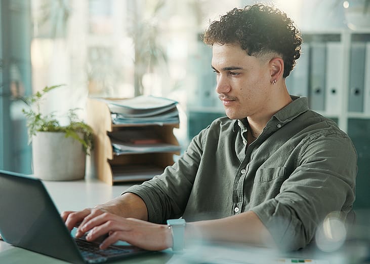 A male employee at work using a laptop.
