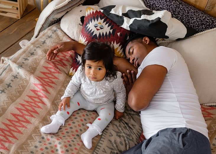 A father sleeps beside his young daughter.
