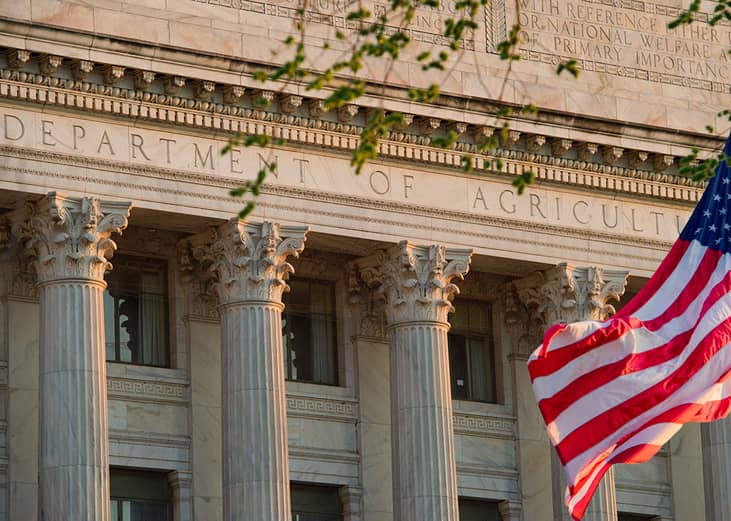 The facade view of the United States' Department of Agriculture office building with the American flag in the front.