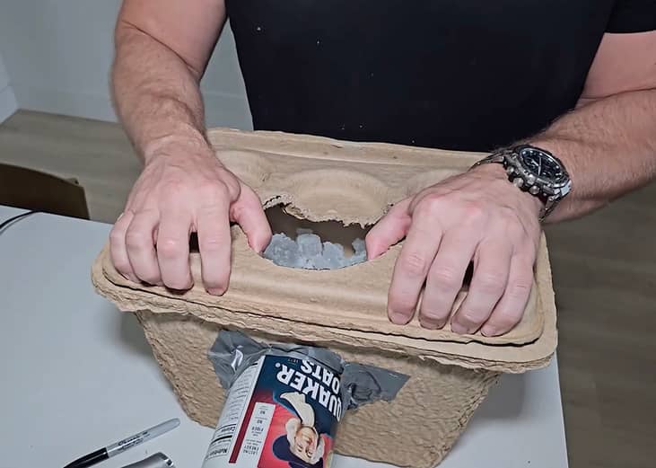 Man creating a DIY air conditioner at home using thick cartons.