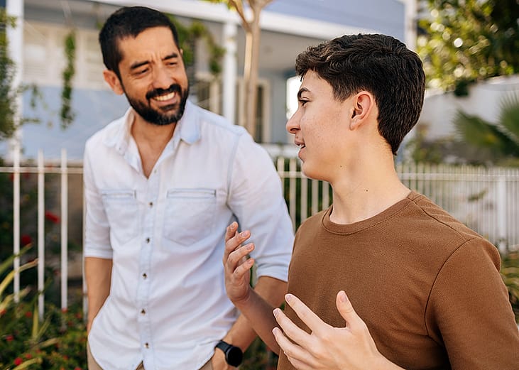 A teenage son sharing stories with his father during an outdoor walk.