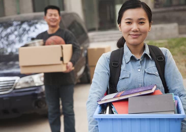A student carrying her things outside the college dormitory before move-in.
