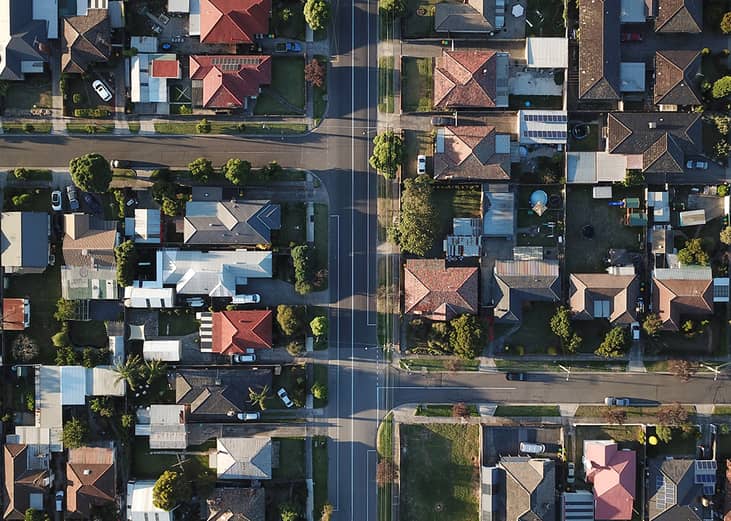 An aerial shot of a downtown street seen through its house rooftops and symmetrical roads during sunset.