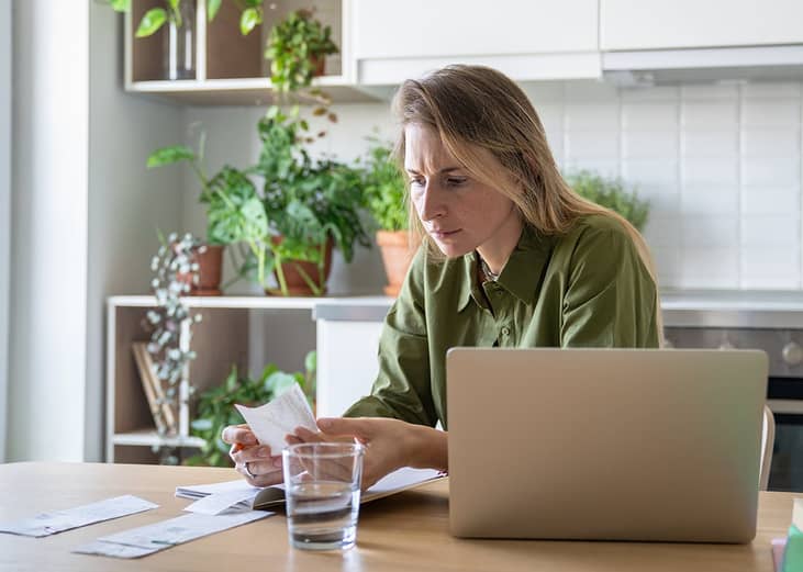 A person checking receipts and financial statements from different expenses at home.