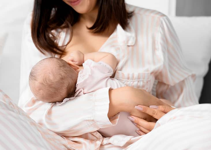 A mother breastfeeding her baby in the bedroom.