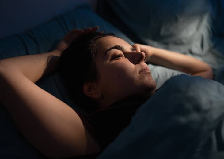 A woman drifts into sleep at night.