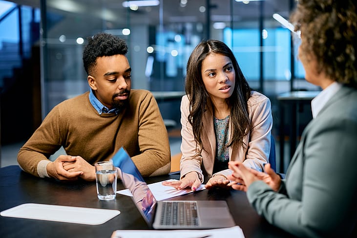 A married couple raising their insurance policy concerns to a financial advisor in an office.