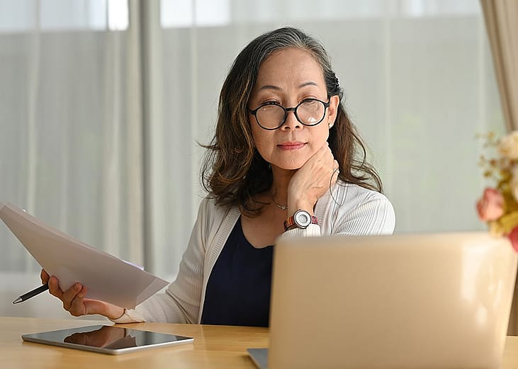 A senior woman reviewing financial documents at home.